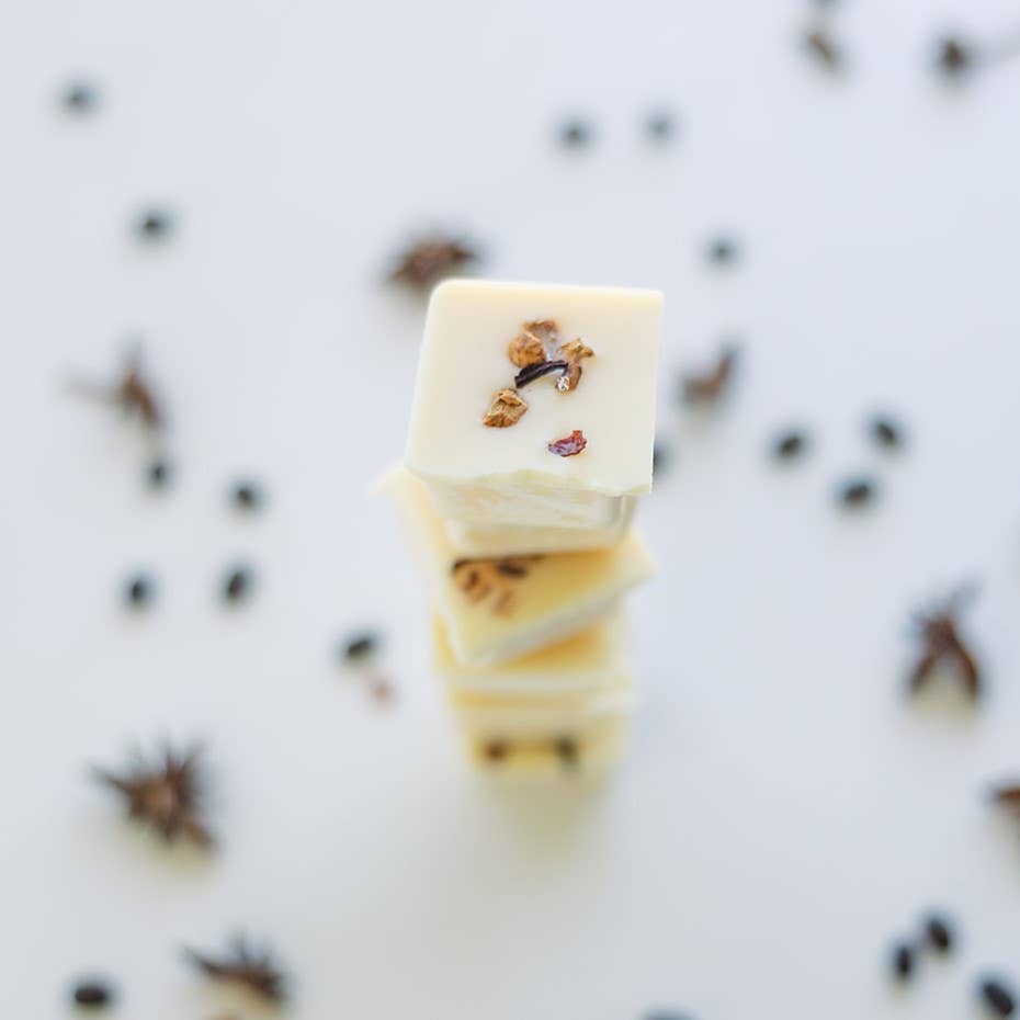 Image of the Cardamom Latte wax melt, an off-white wax decorated with dried spices, broken into six individual blocks and stacked on top of each other.