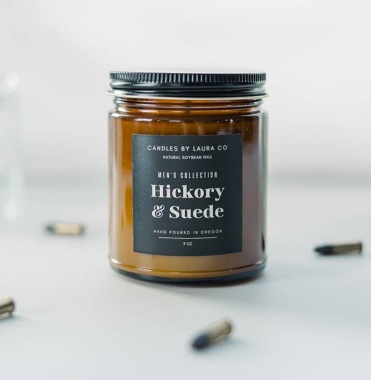 A candle in an amber-tinted mason jar, labeled “Hickory & Suede”.
