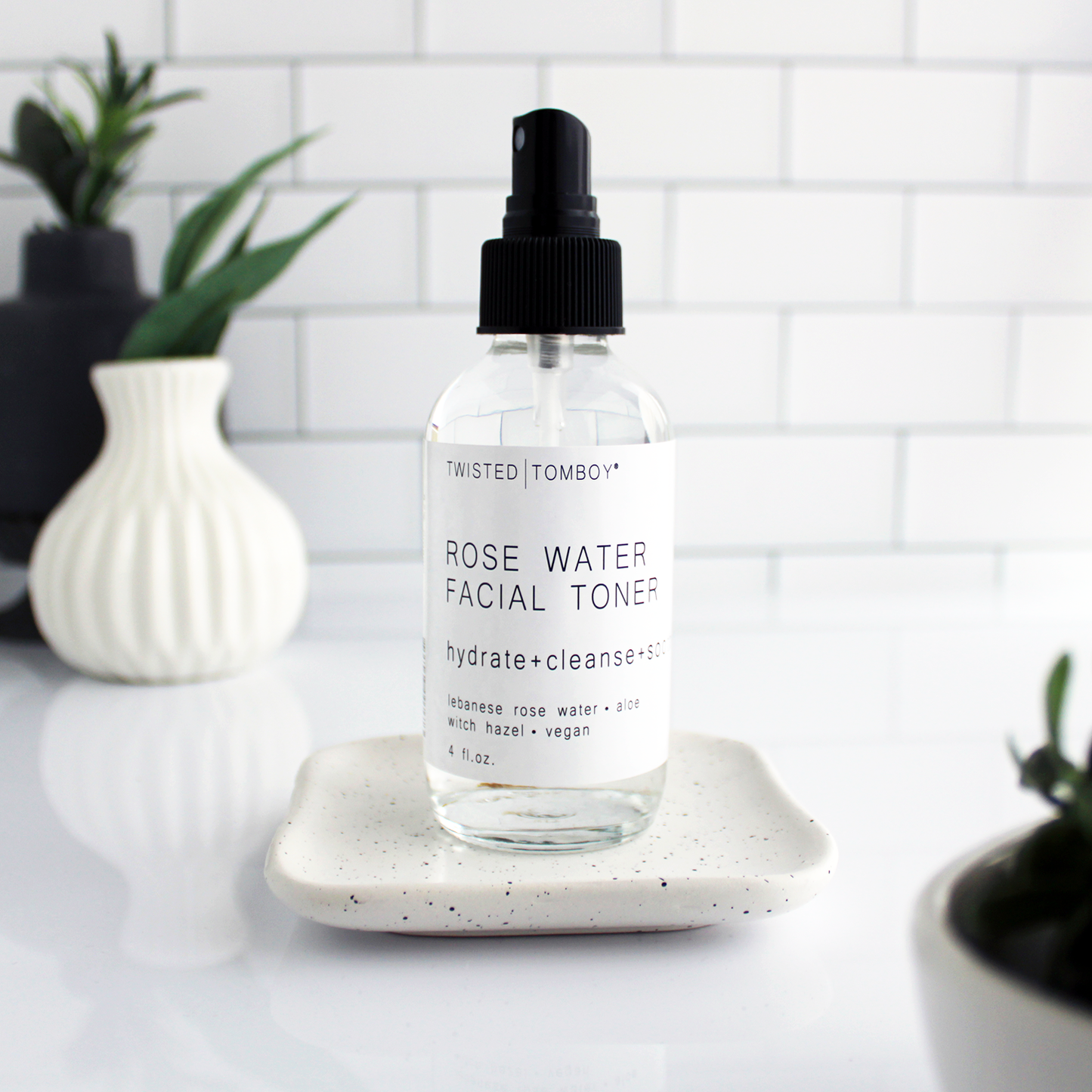 A glass bottle filled with a clear liquid, labeled “Rose Water Facial Toner - hydrate+cleanse”