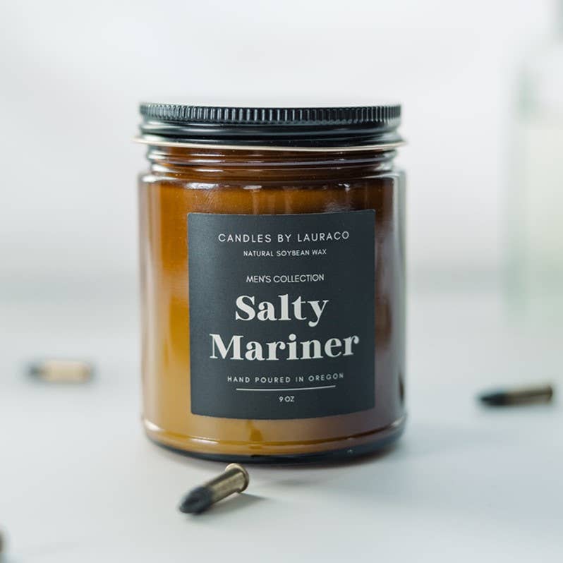 A candle in an amber-tinted jar labeled “Salty Mariner”.