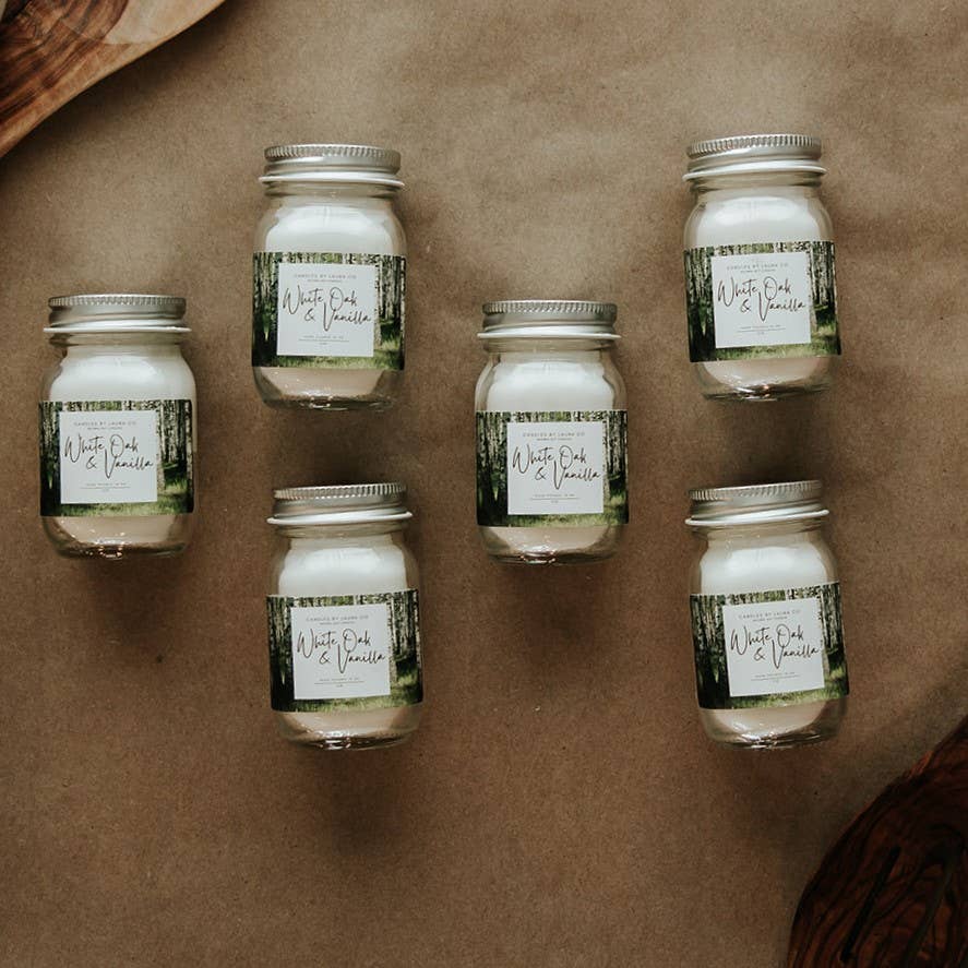 An image of six White Oak & Vanilla candles, off-white candles in miniature mason jars.