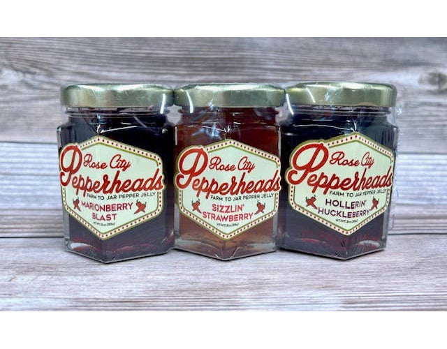 Three jars of jam shrink-wrapped together into a package. Flavors are Marionberry Blast, Sizzlin’ Strawberry, and Hollerin’ Huckleberry.