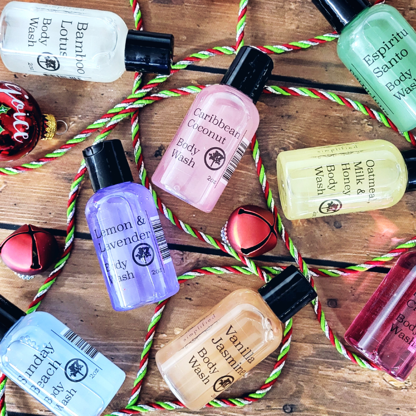 Various bottles of travel-size body wash on a wooden surface with Christmas decorations.