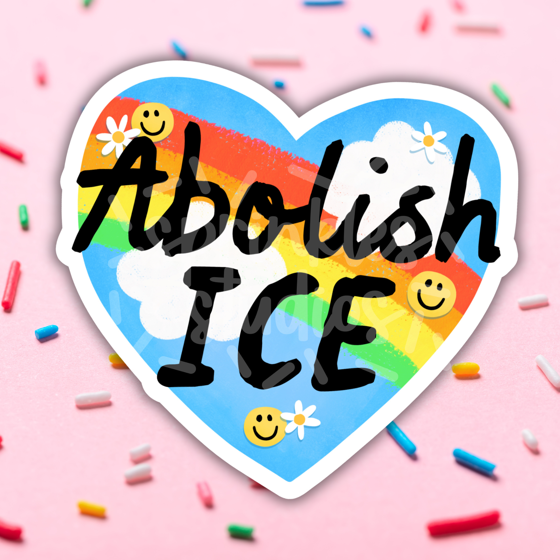 Image of a sticker shaped like a heart, showing a sunny sky with a rainbow and the words “Abolish ICE” over the image.