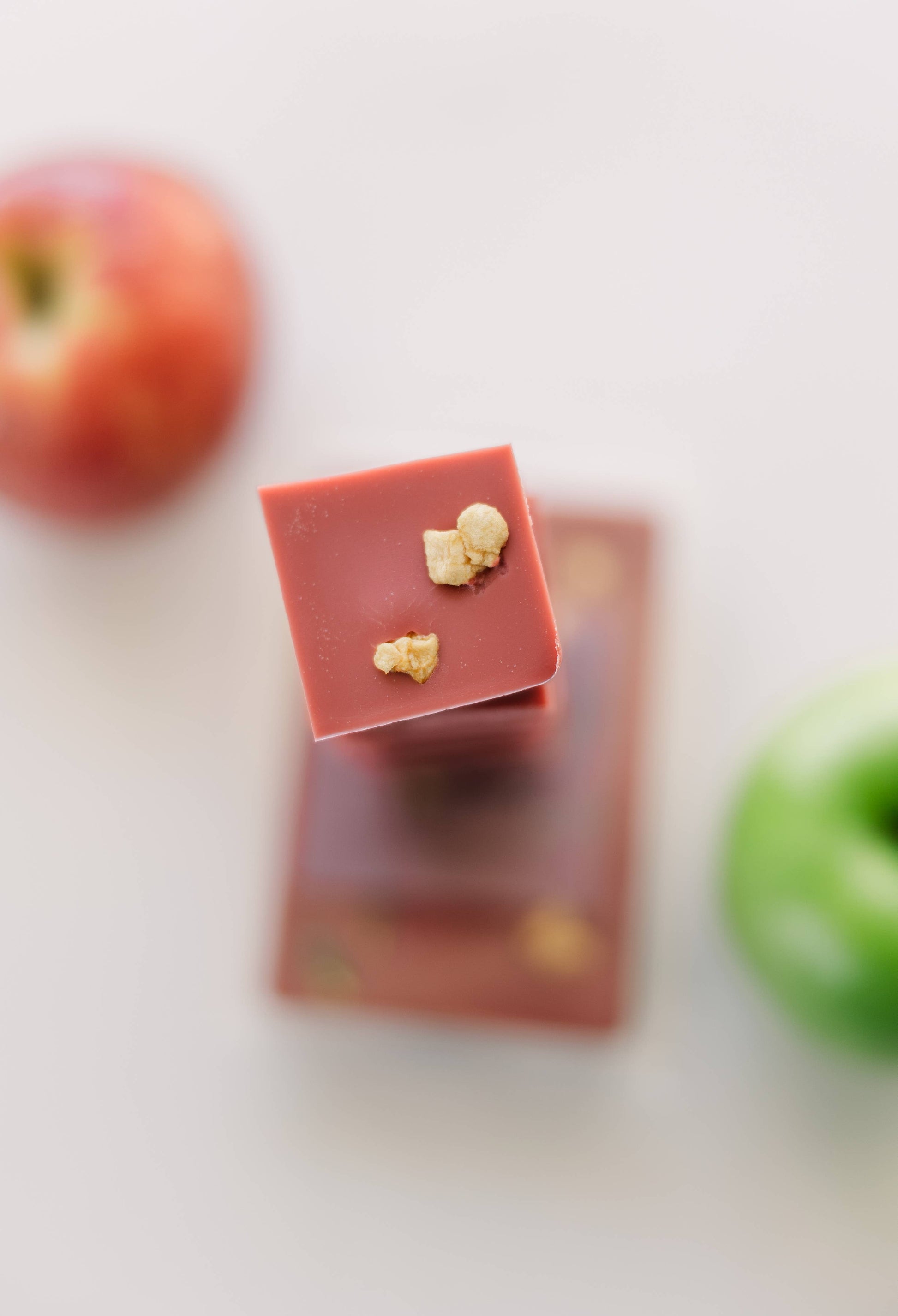 Image of two Apple Harvest wax melts, red wax decorated with dried spices. One of them is broken into six individual blocks and stacked on top of the other.