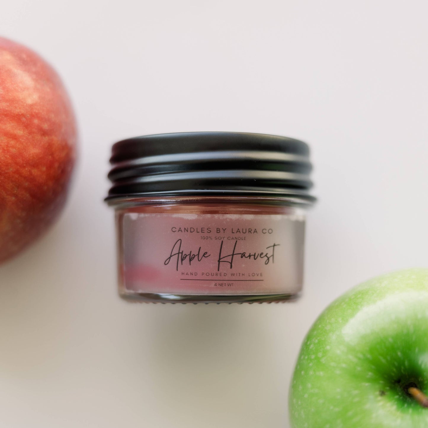 Image of the Apple Harvest candle, a red candle in a squat jar with a black lid.