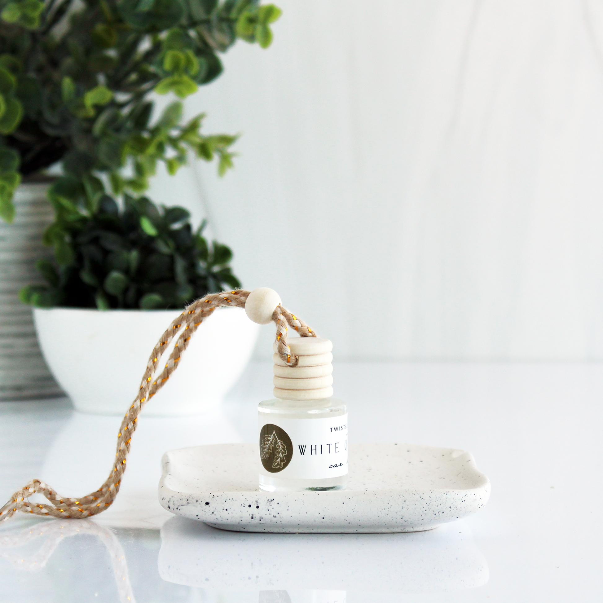 A small bottle of clear liquid with a cord attached to the lid allowing it to be hung up. The bottle is rotated at an angle that doesn’t allow the full label to be read, but the word “White” is visible.