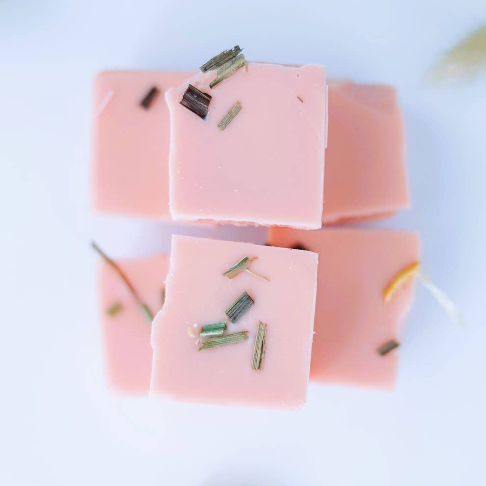 Image of the six pieces of the Citrus Agave wax melt broken apart, individual squares of pink wax topped with lemongrass and dried citrus fruit, stacked in a pyramid shape.