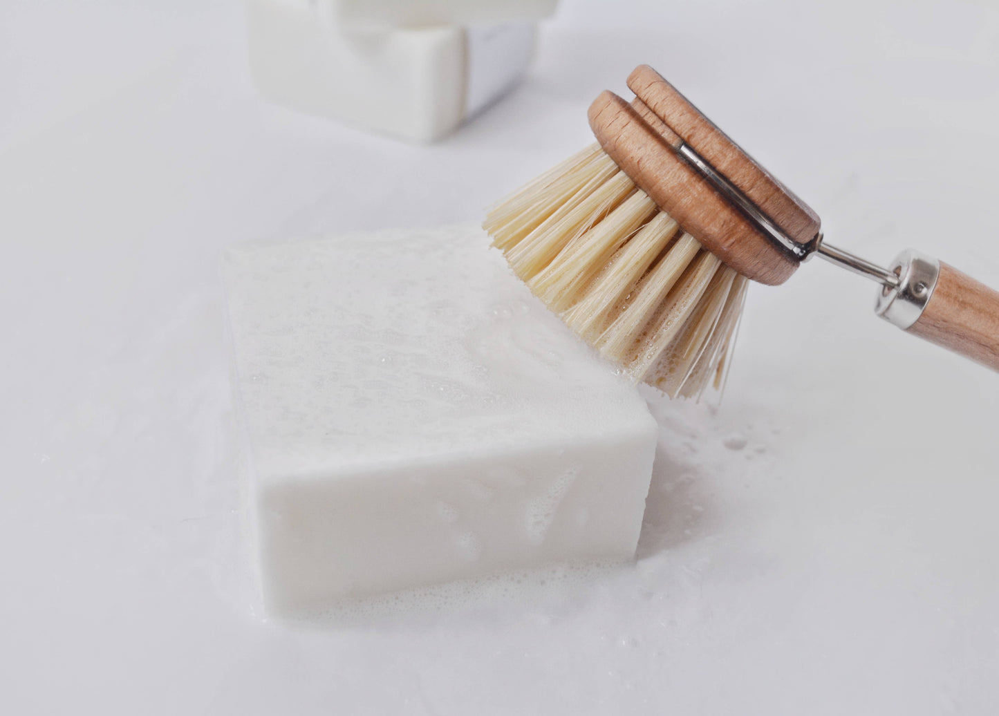 Shows a dish soap bar being scrubbed by a dish brush, creating lather.