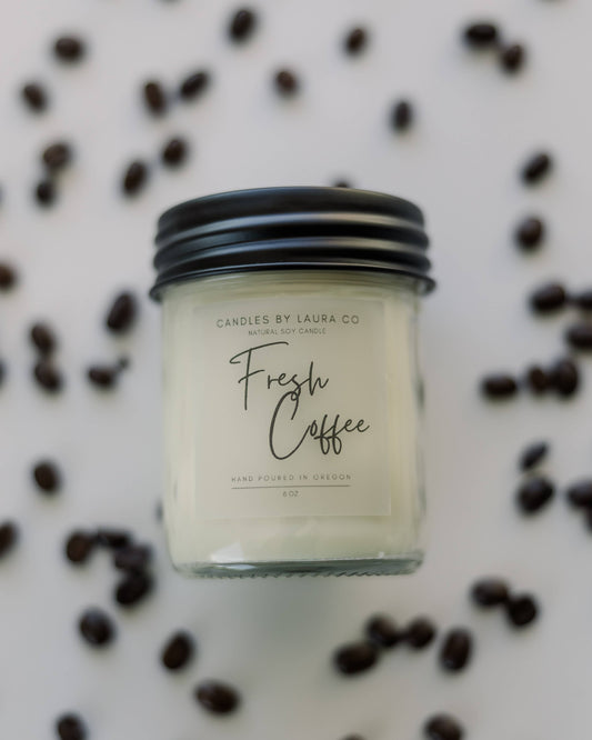 An image of the Fresh Coffee candle, an off-white candle in a jar with a black lid.
