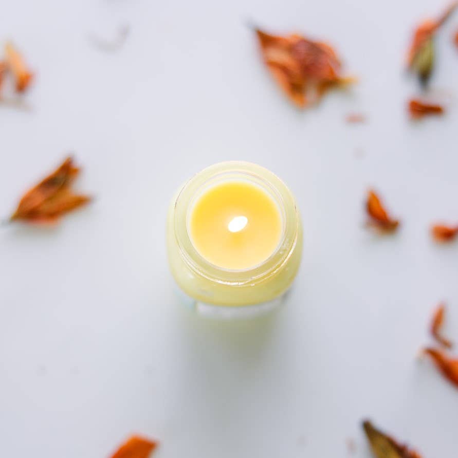 Image of the Jamaica Me Crazy candle, a yellow candle in a miniature mason jar, with the lid removed and the candle lit.