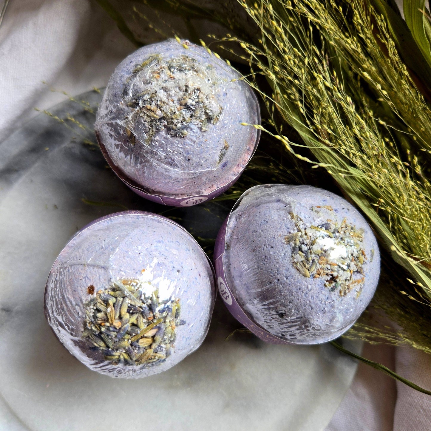 A trio of Lavender bath bombs, purple bath bombs topped with lavender buds.