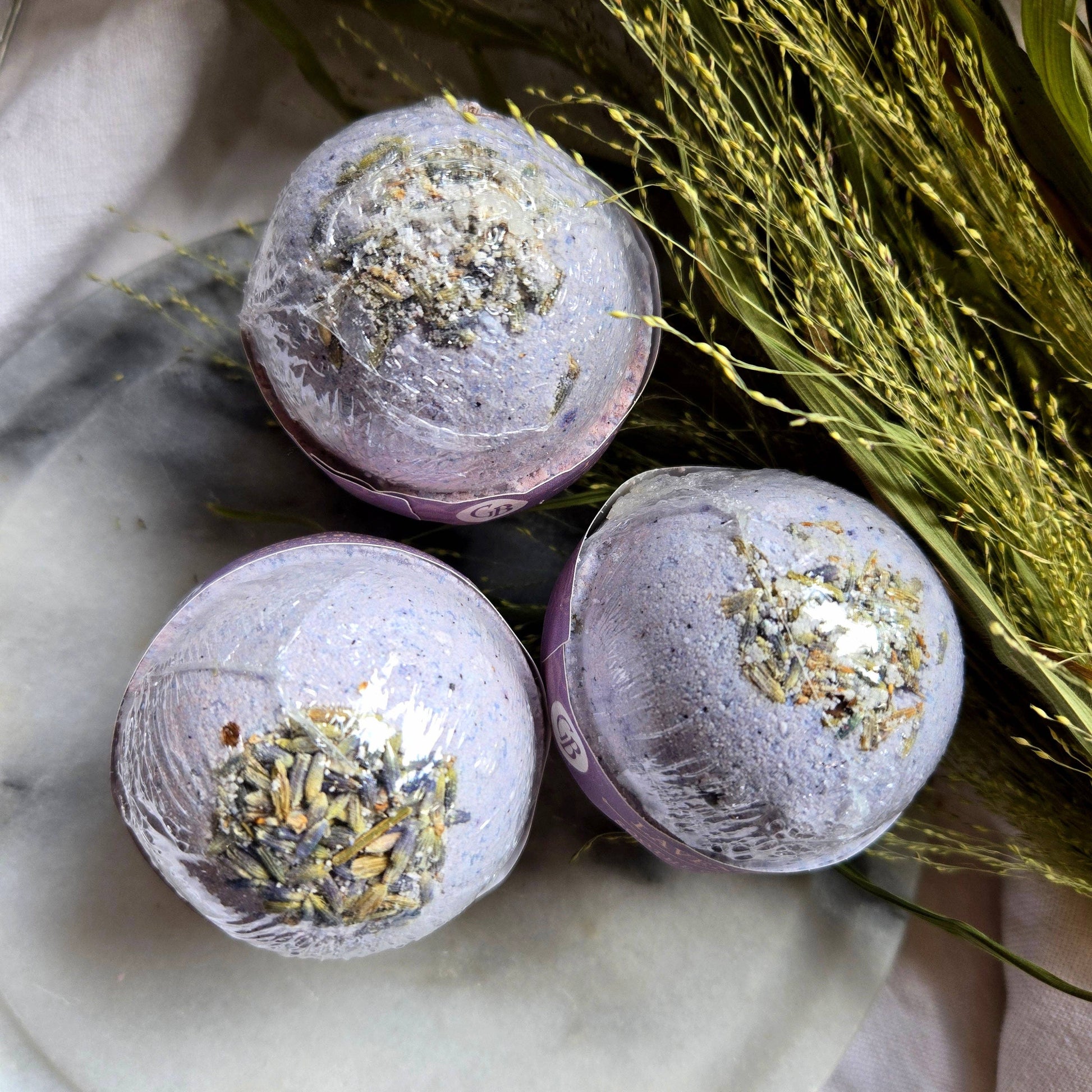 A trio of Lavender bath bombs, purple bath bombs topped with lavender buds.