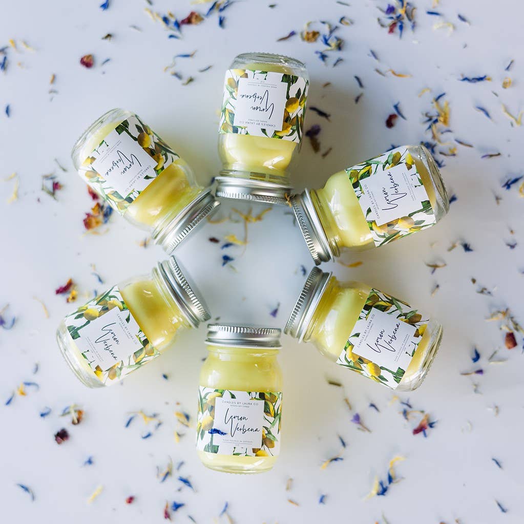 Image of six Lemon Verbena candles, yellow candles in miniature mason jars, laid out in a circle.