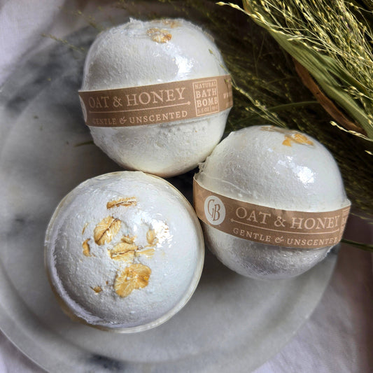 A trio of Oat & Honey bath bombs, which are white bath bombs topped with oats.