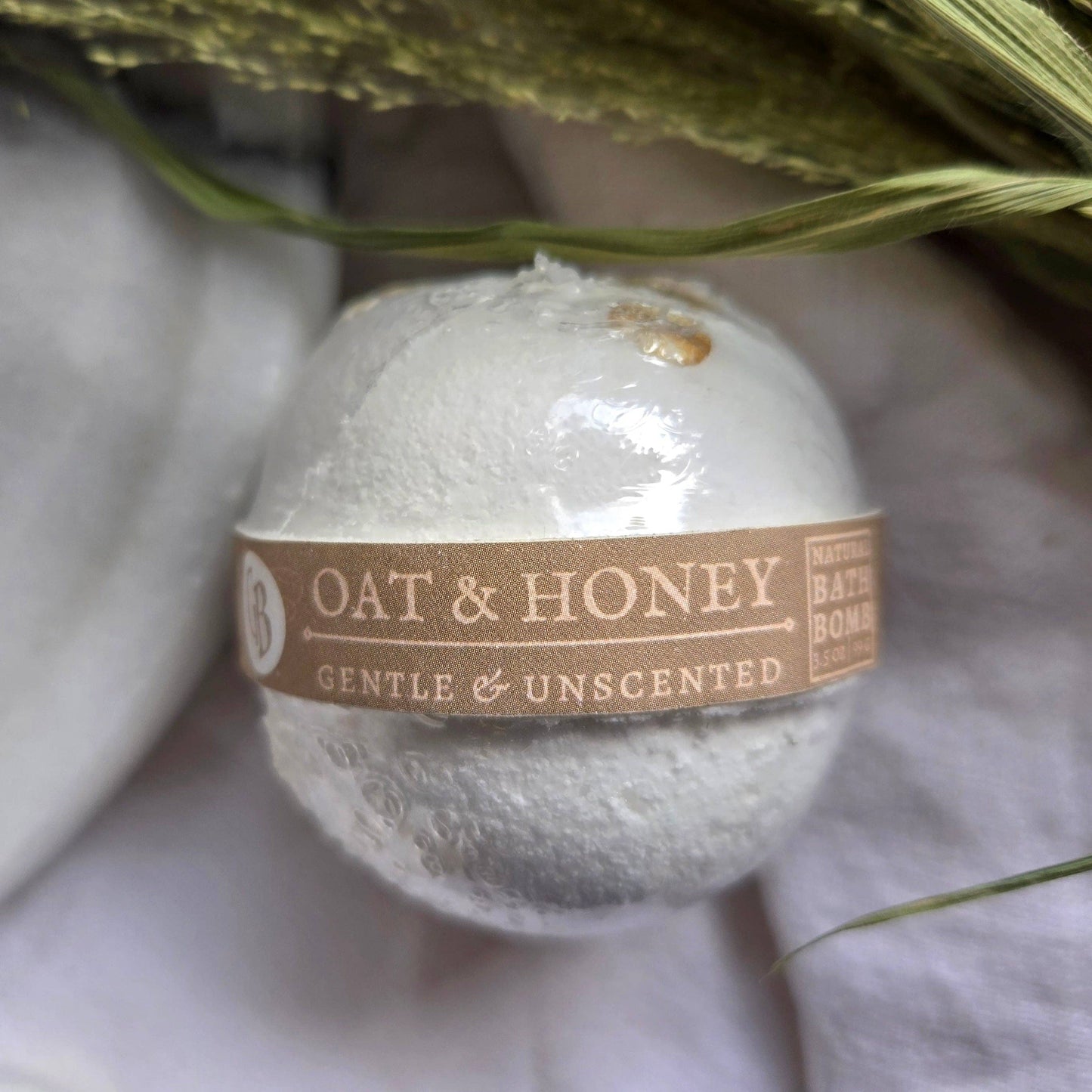 A white bath bomb labeled “Oat & Honey” with the tagline “Gentle & Unscented”.