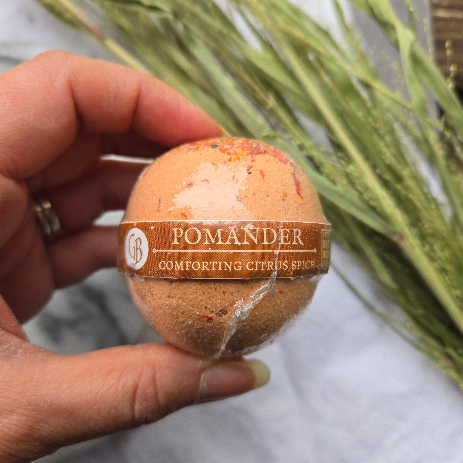 An orange bath bomb labeled “Pomander” with the tagline “Comforting Citrus Spice.”