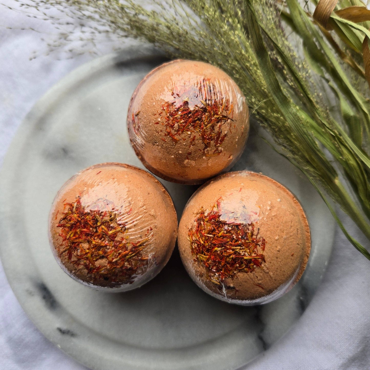 A trio of Pomander bath bombs, orange bath bombs tapped with safflower petals.