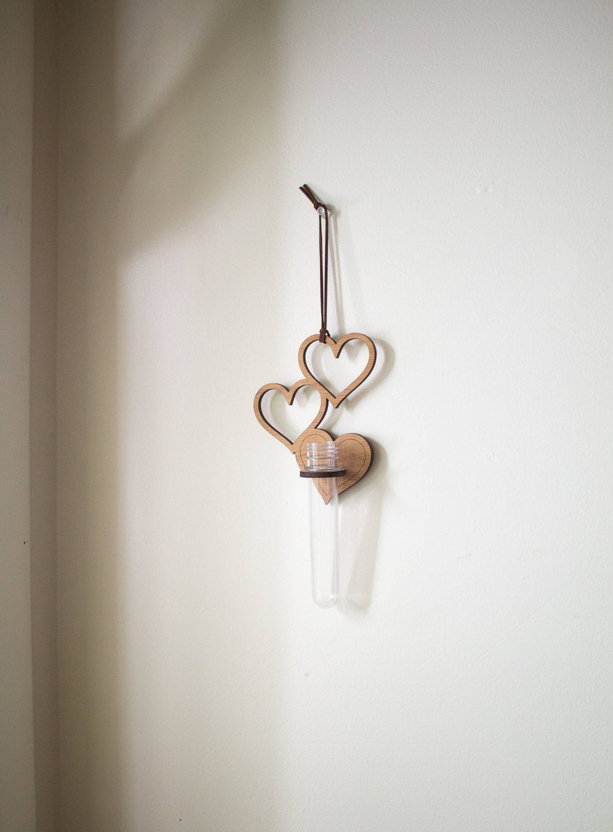 A few hanging wooden hearts, with a wooden ring holding up a clear test tube. 