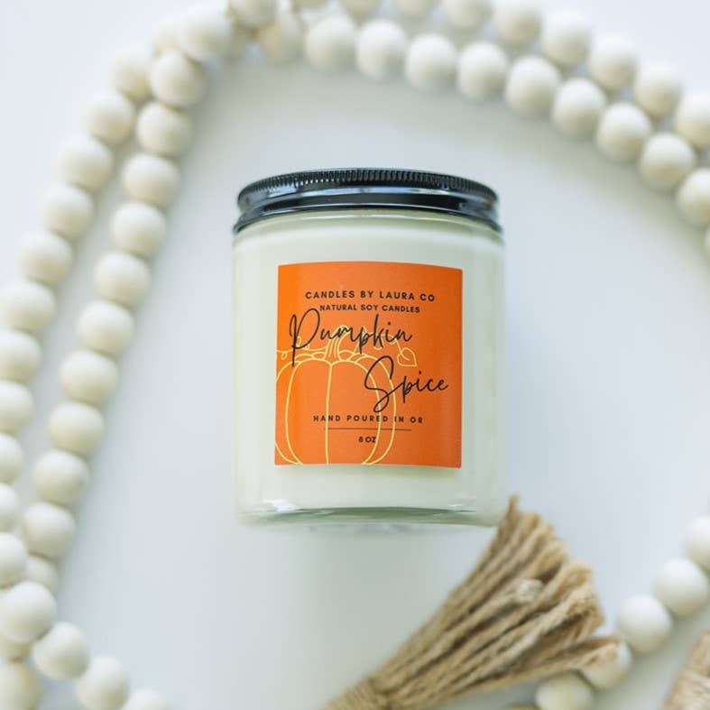Image of the Pumpkin Spice candle, a white candle in a jar with an orange label and a black lid.