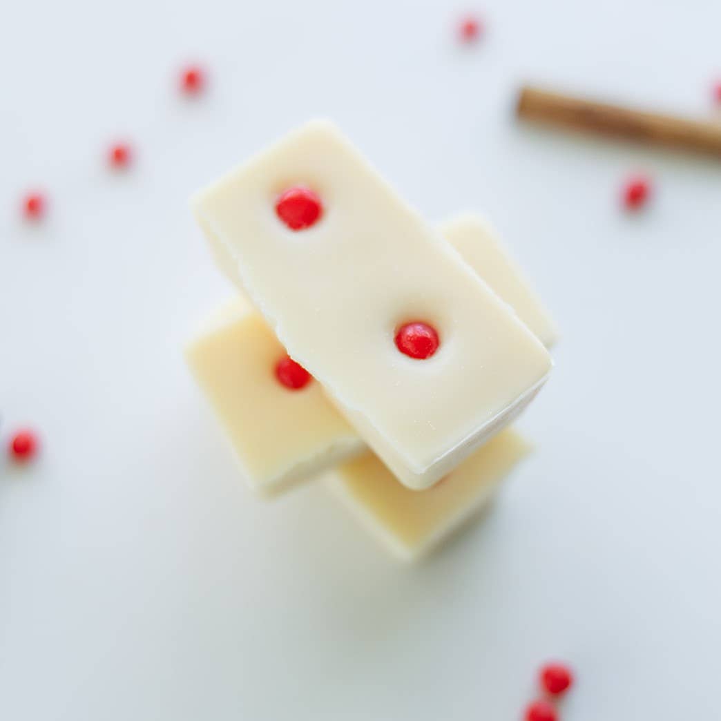 Image of the Red Hot Cinnamon wax melt, a white wax dotted with bright red pieces, broken apart into three pairs of two blocks stacked on top of each other.
