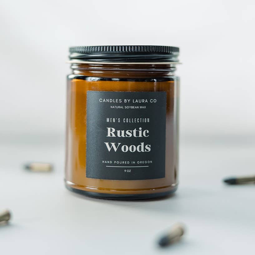 A candle in an amber-tinted jar, labeled “Rustic Woods”.