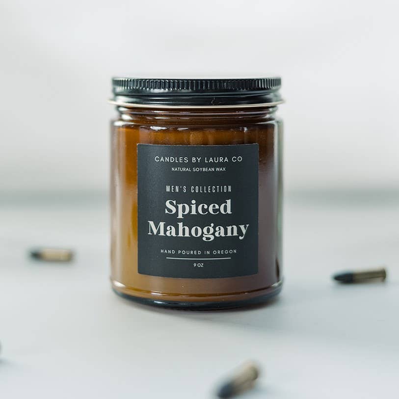 A candle in an amber-tinted jar labeled “Spiced Mahogany.”