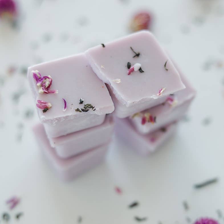Image of the Vanilla Orchid wax melt, a pale lavender wax decorated with shredded flowers, broken into six blocks and placed in two stacks of three each.