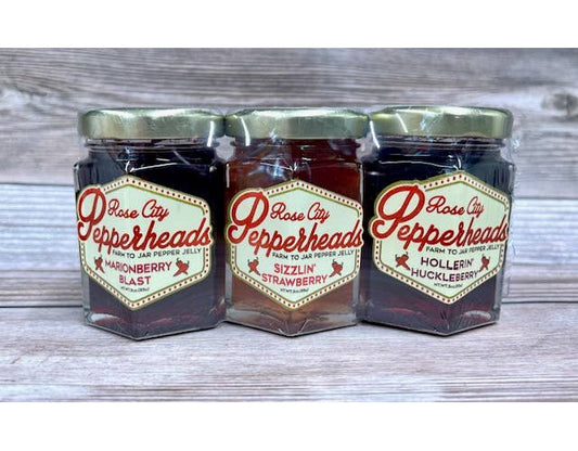 Three jars of jam shrink-wrapped together into a package. Flavors are Marionberry Blast, Sizzlin’ Strawberry, and Hollerin’ Huckleberry.