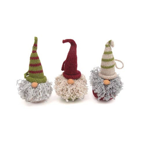 Three small knitted gnome ornaments with pointed hats and curly faux-fur beards, shown on a plain white background. The left gnome has a green and red striped hat and gray beard, the center gnome has a dark red hat and cream beard, and the right gnome has a cream and green striped hat with gray beard.