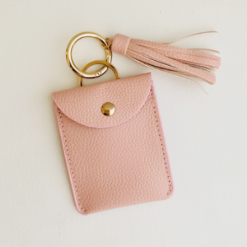Pink leather keychain pouch with tassel on a light beige background