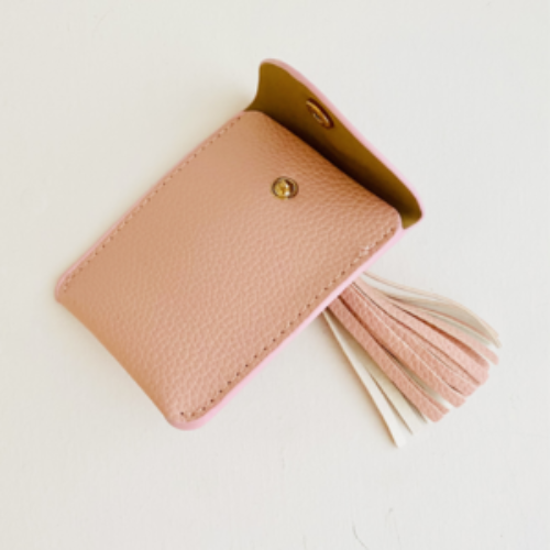 Pink leather cardholder with tassel and flap opened on a white background