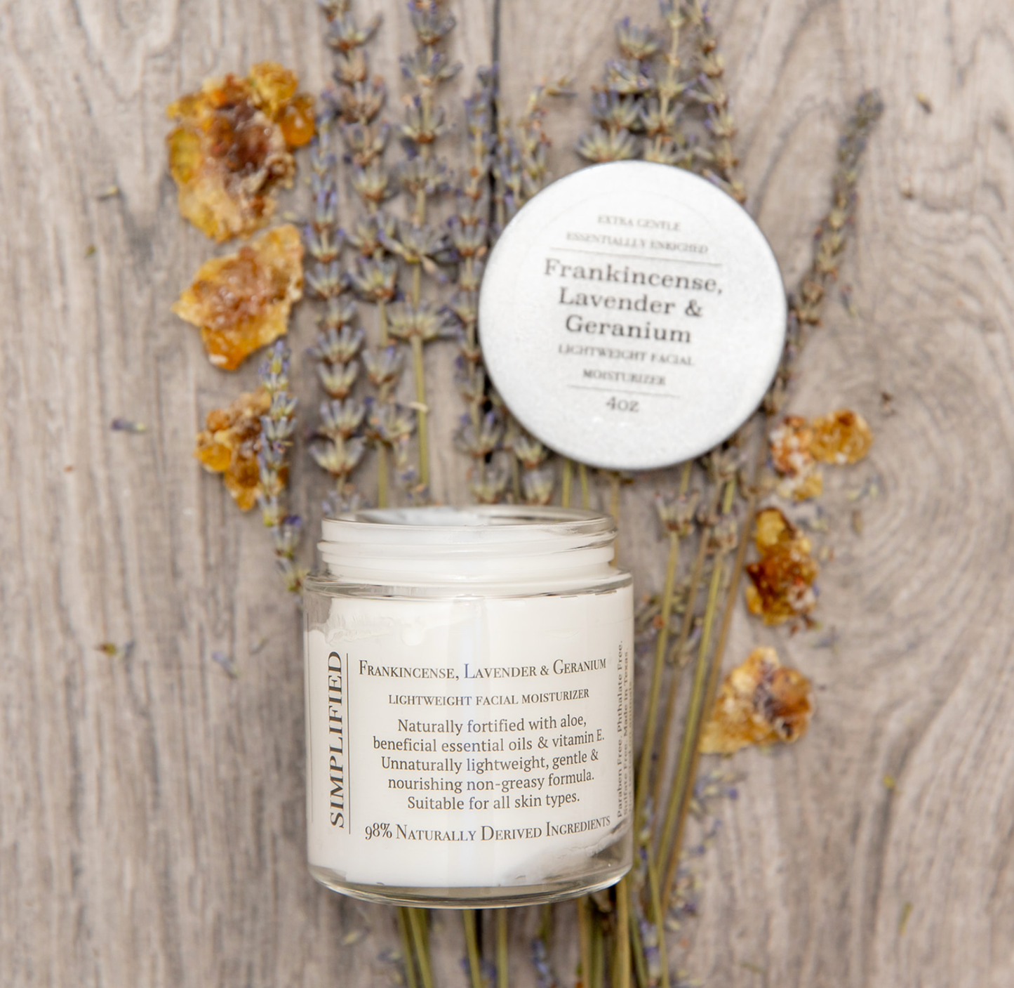 Facial moisturizer jar with lid on a wooden surface with dried flowers