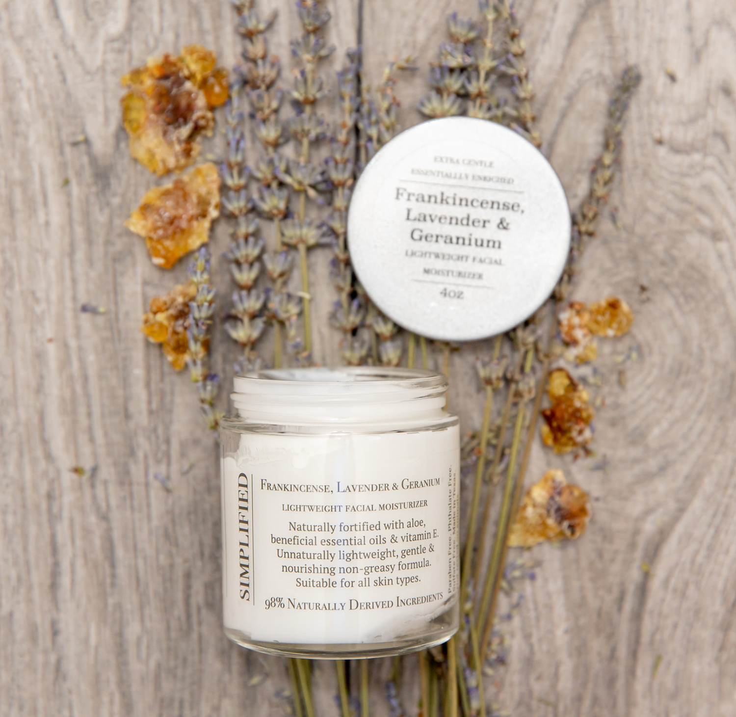Facial moisturizer jar with lid on a wooden surface with dried flowers