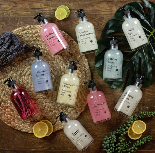 Assorted bottles of hand soaps on a wooden surface with decorative elements.