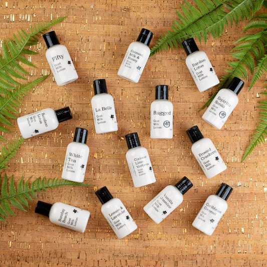 Multiple small bottles of lotion arranged on a cork background with green leaves.